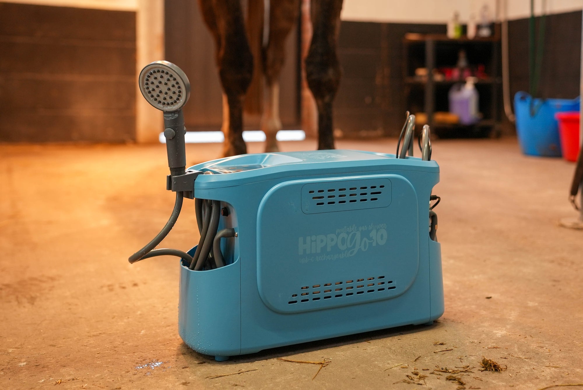 Blue grooming device with horse legs in the background