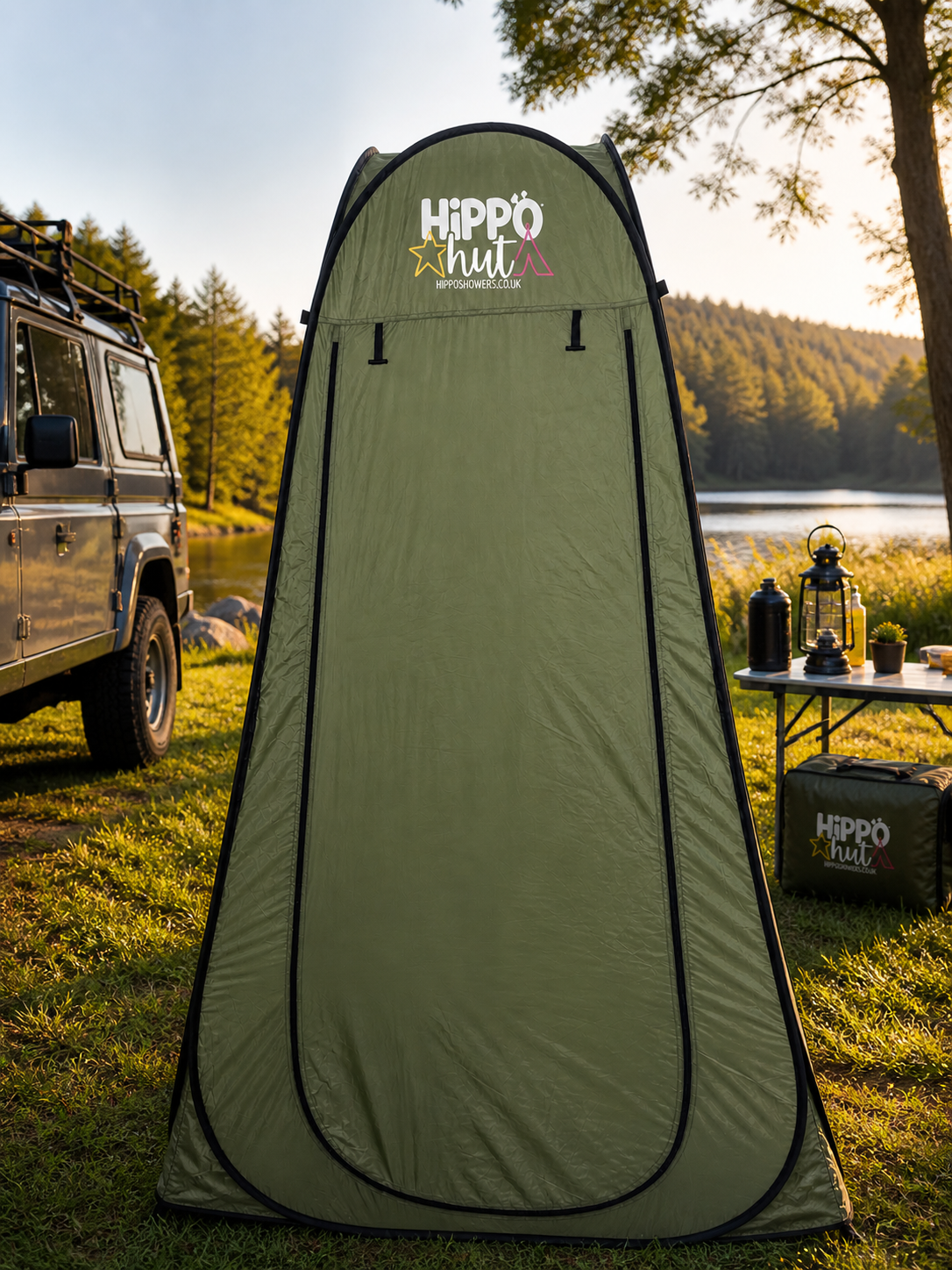Green portable shower tent with 'Hippo Hut' branding in a camping setting.